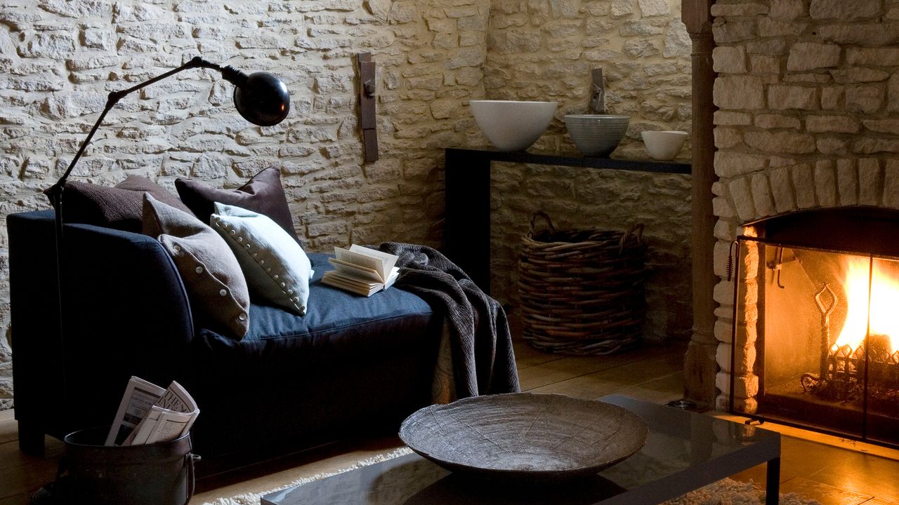 Living room with exposed brick walls, blue sofa, floor reading lamp and fireplace