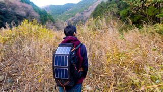 Man walking into wilderness with solar cells on his backpack
