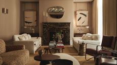 Elegant neutral living room with a mix of armchairs and coffee tables and a large dark stone fireplace