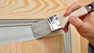 Close up of paintbrush painting bare wood panel door