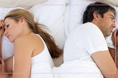 Unhappy couple laying back to back in bed
