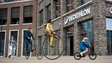A child, BMXer, lady on a classic style bike and gentlemen on a penny farthing riding into a Decathlon store