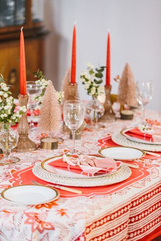 A dining table laid for Christmas dinner with red and white themed decor