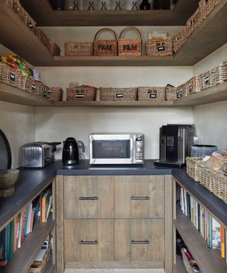 inside of walk in pantry with open shelves, drawers, wicker basket on shelves and worktop space for small appliances