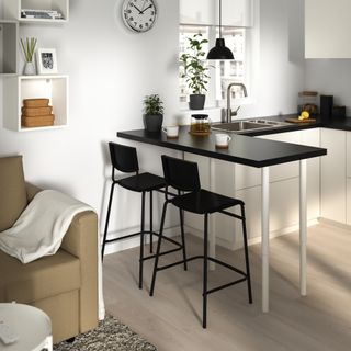 small kitchen with U-shape units, breakfast bar, corner of sofa, black stools