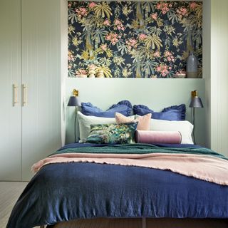 Green bedroom with built-in wardrobes either side of the bed and wallpaper in between
