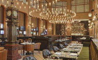 W Hotel dining hall with grandfather clock, chandeliers leather tub chairs and green banquette seating