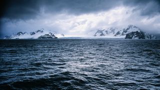 Photo of dark waves against a backdrop in Antarctica, with dark clouds