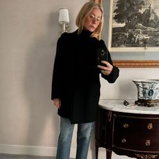 Gwyneth Paltrow wears a black turtleneck sweater with blue jeans and white sneakers.