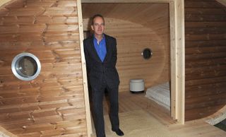 Kevin McCloud standing in a wooden hut at Grand Designs live