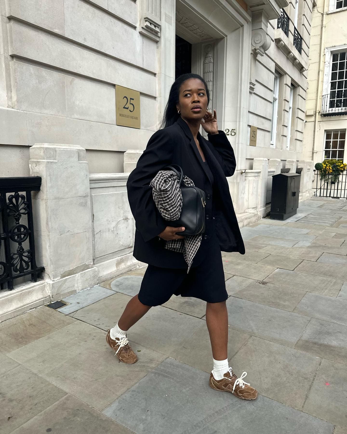Influencer Marilyn wears brown suede sneakers with long back shorts and an oversize blazer.