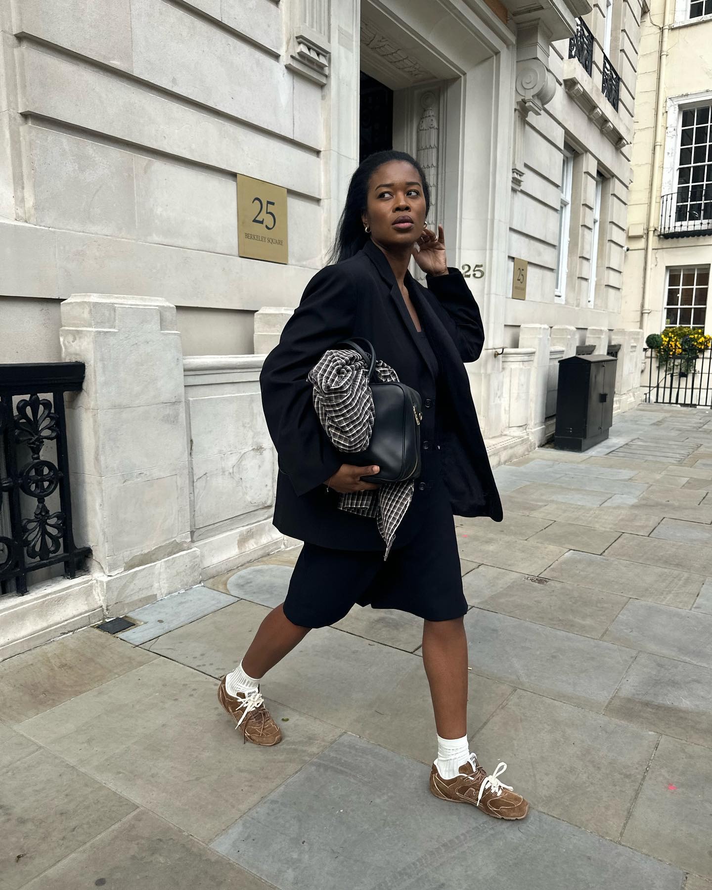 Influencer Marilyn wears brown suede sneakers with long back shorts and an oversize blazer.