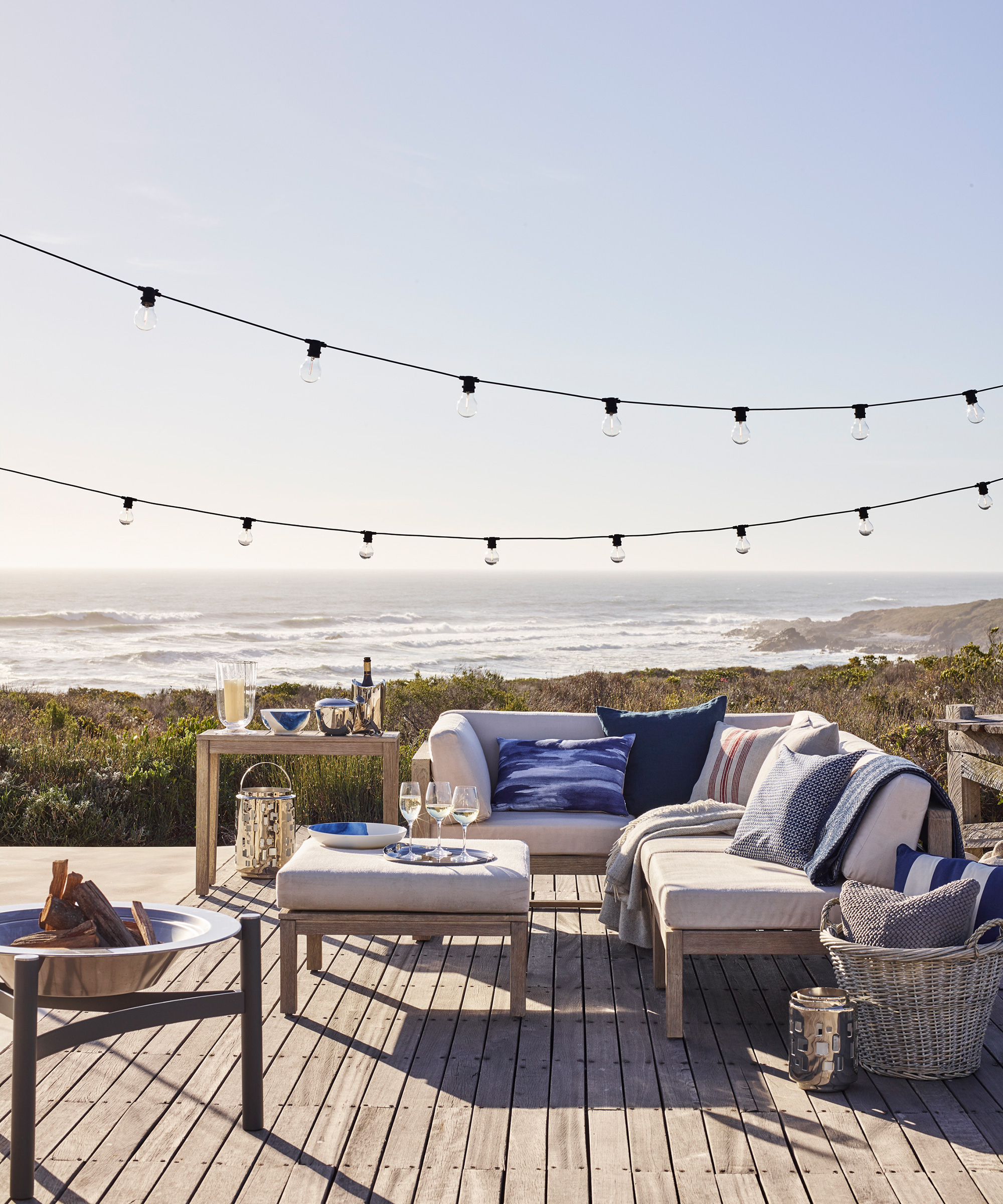 A wooden deck with an outdoor sofa looking out over a seascape