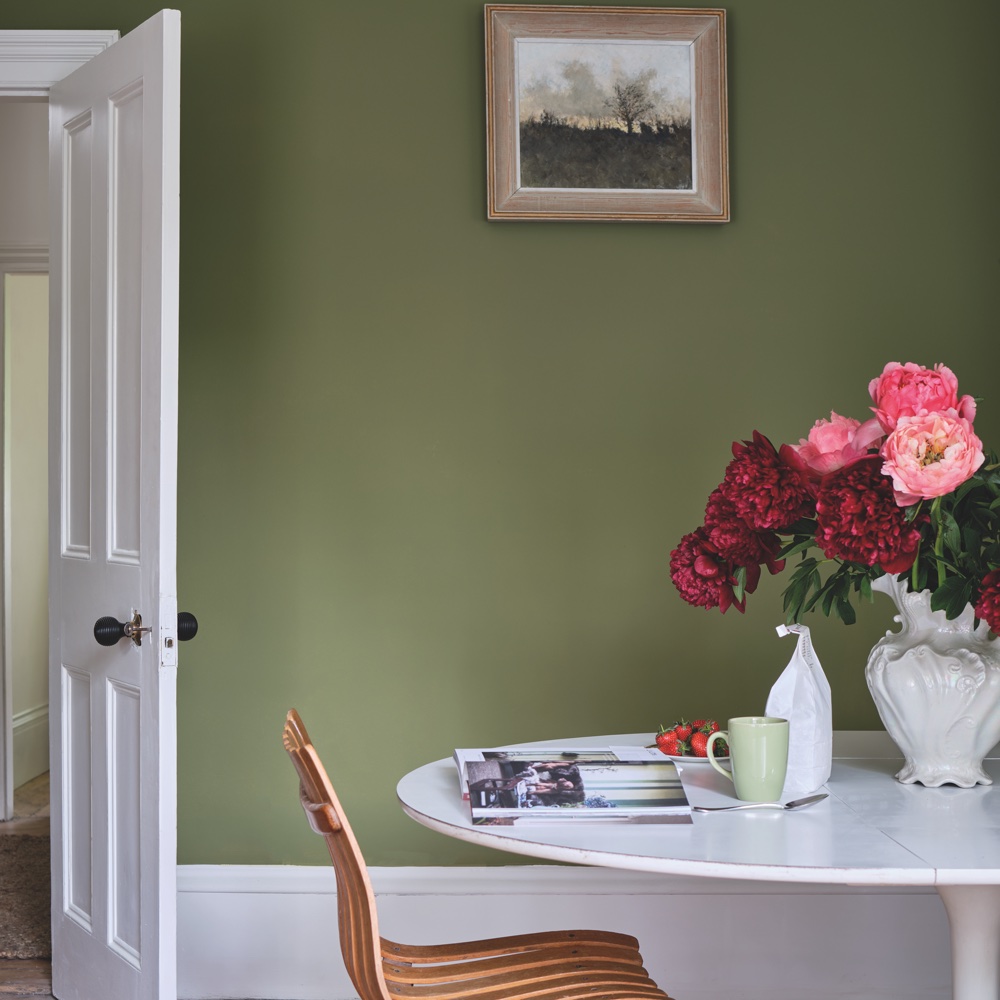 living area with green wall and white door and round table with chairs