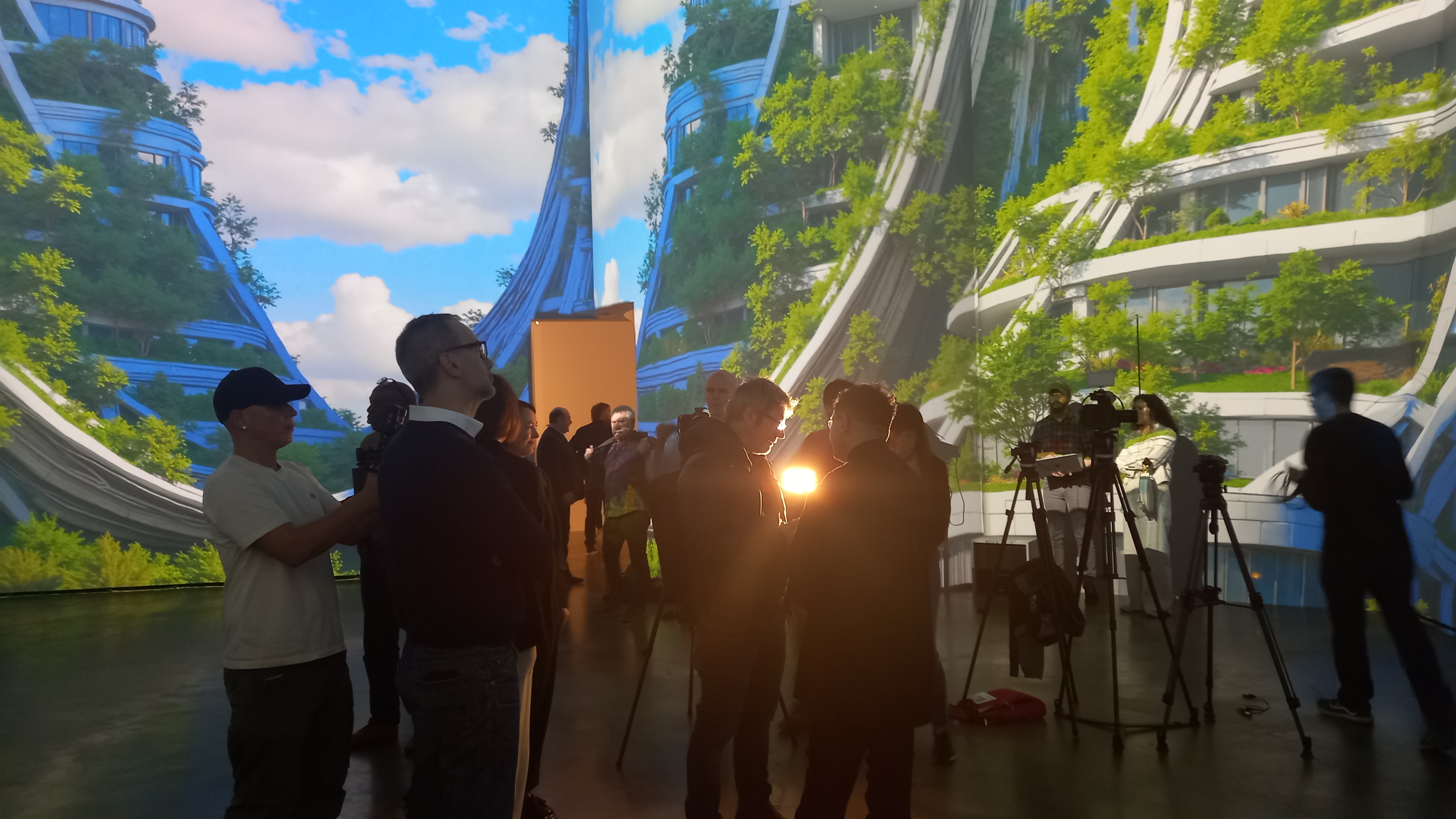 Journalists and camera crews gather inside the Guggenheim Bilbao, surrounded by floor-to-ceiling digital projections of green, curving skyscraper-like structures.