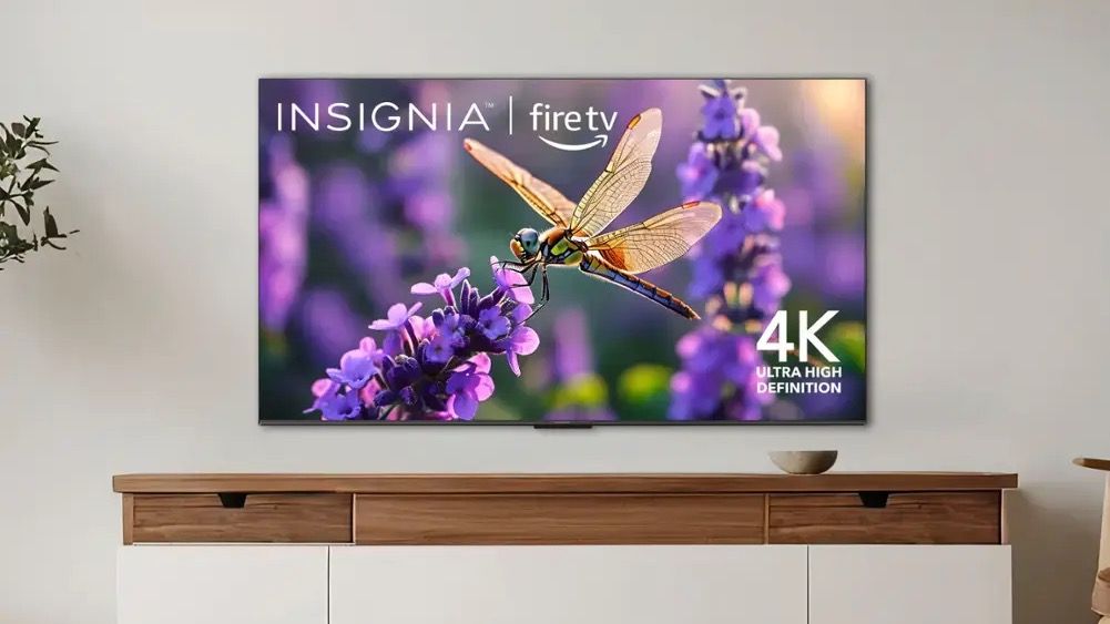 An Insignia F30 TV wall-mounted above a cabinet.