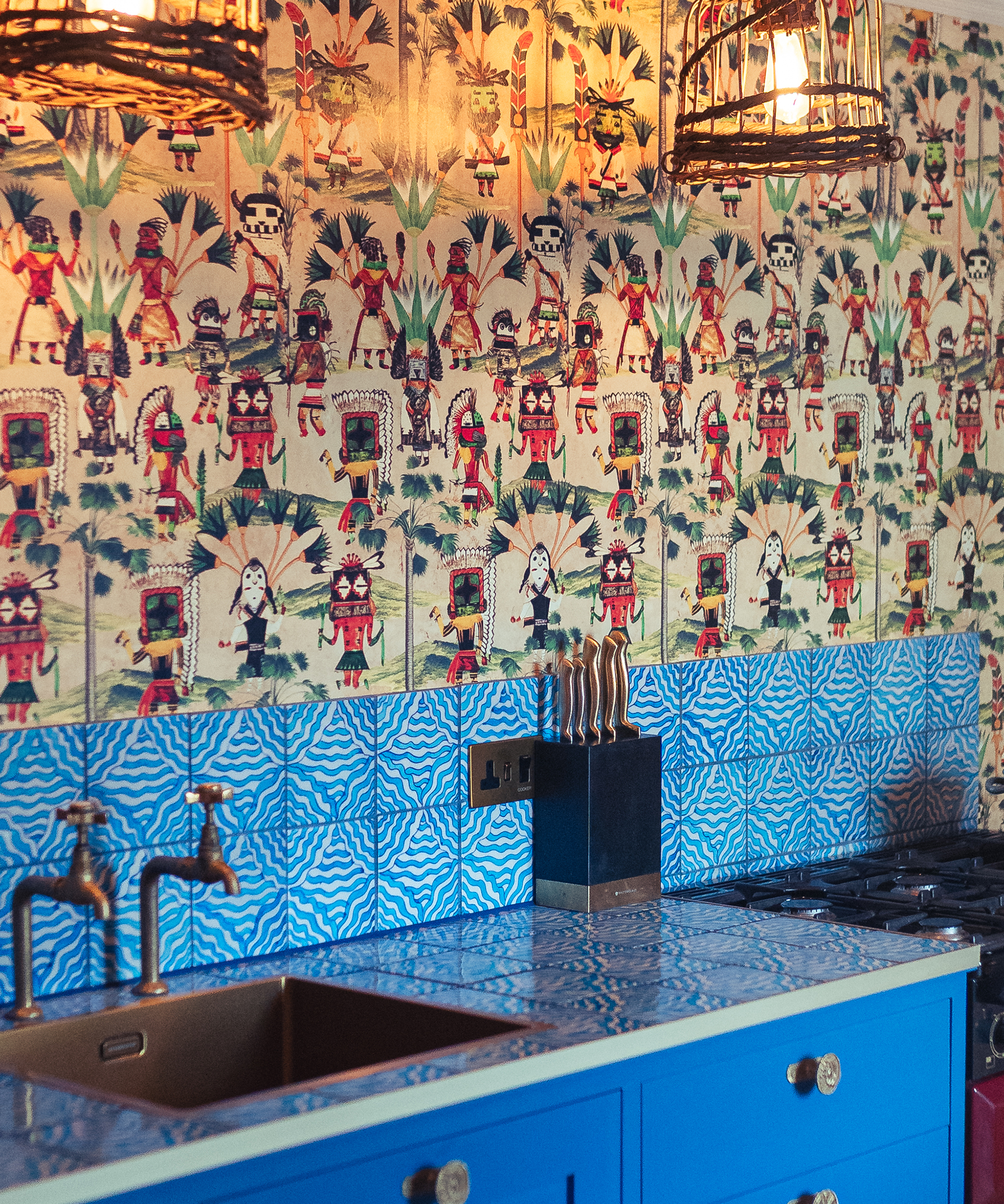blue kitchen with patterned wallpaper above blue tiles