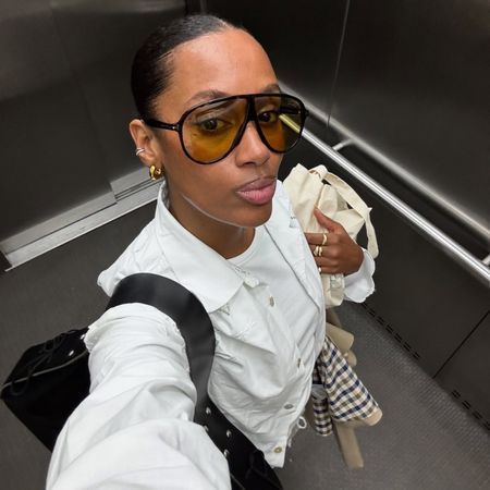 Woman takes an elevator selfie in large aviator sunglasses with yellow-tinted lenses.