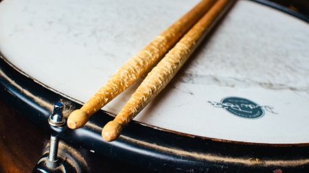 A set of well used drumsticks on a snare drum