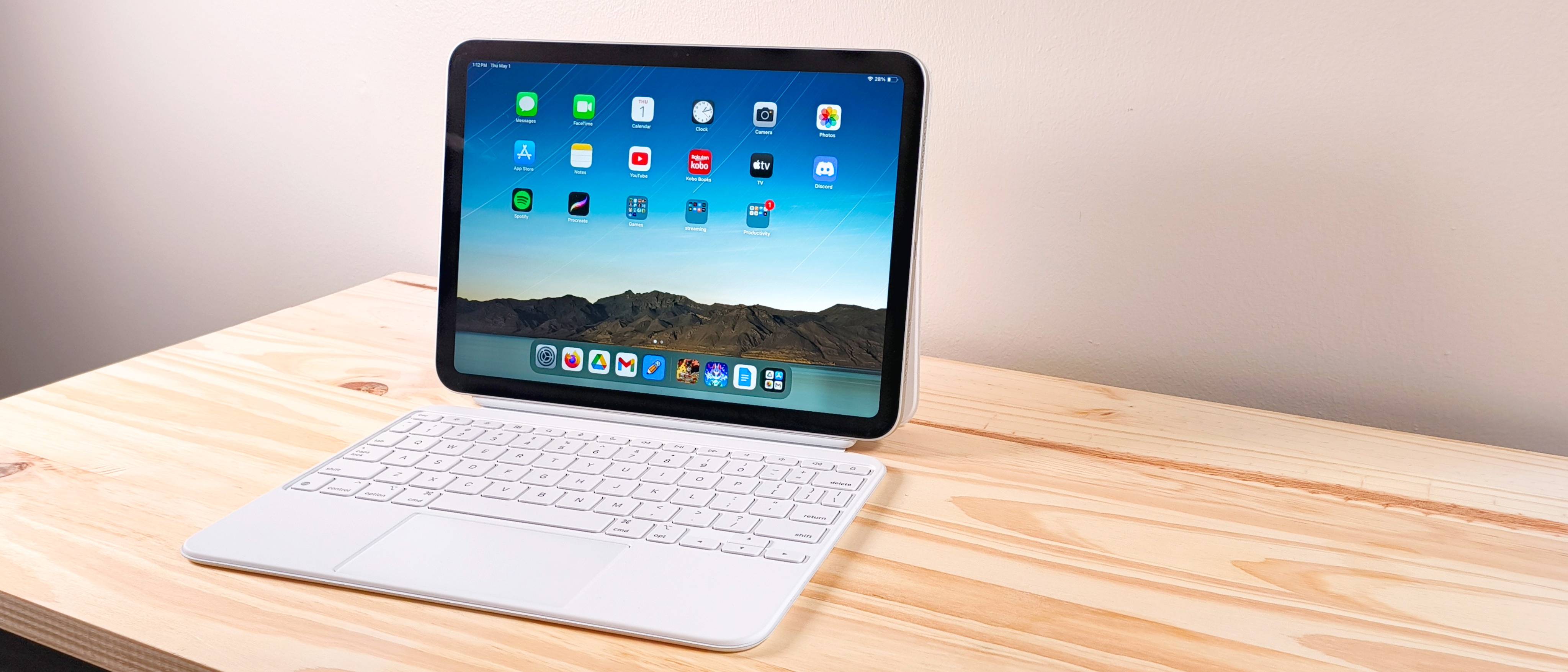 The iPad 11 propped up on a wood table connected to the Magic Keyboard Folio