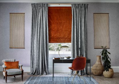 A living room with velvet orange roman blind and black and white patterned curtains