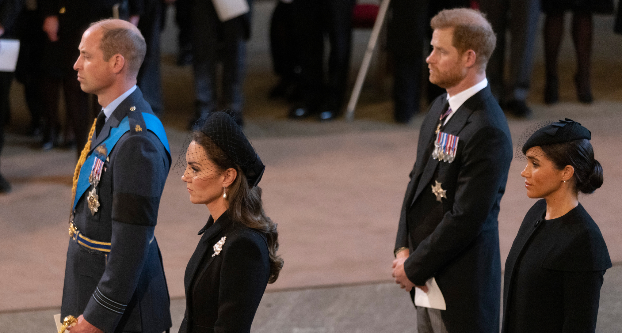 Prince William and Princess Kate standing in front of Prince Harry and Meghan Markle at Queen Elizabeth's funeral