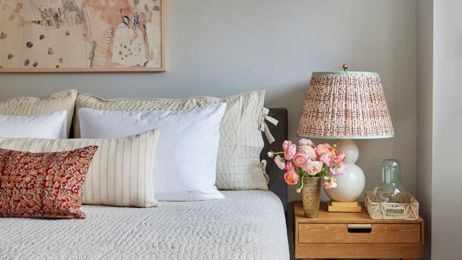 Griege bedroom with wooden bedside table, with fabric lamps and layered white and cream bedding