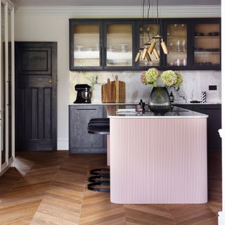 kitchen with pink breakfast bar and bacl cabinets with reeded glass doors
