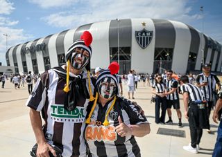 Two Atletico Mineiro fans with their faces painted in club colours outside the club's stadium, 2023