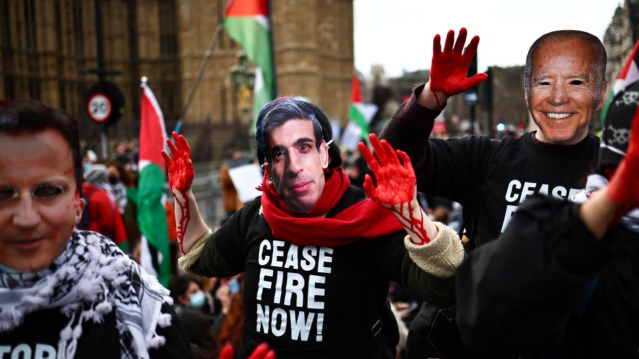 Pro-Palestinian supporters wearing masks picturing Britain&#039;s Foreign Secretary David Cameron (L), Britain&#039;s Prime Minister Rishi Sunak (C) and US President Joe Biden (R) with their hands painted in red march by the Palace of Westminster