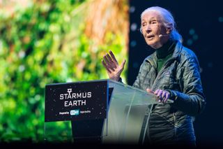 a woman stands at a podium with the words Starmus Earth written on the front of it.