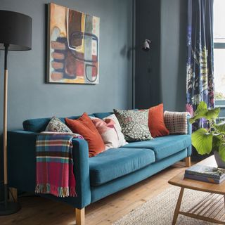 Living room with blue velvet sofa and bright cushions.