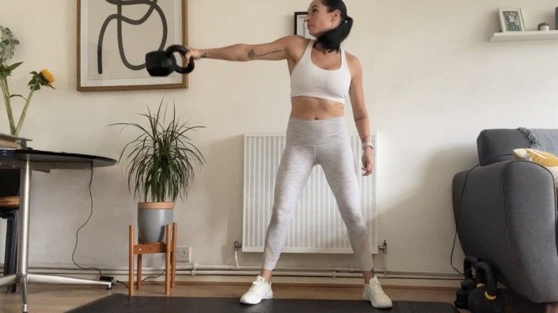 Writer Sam swinging a kettlebell up to her side during lateral kettlebell swings