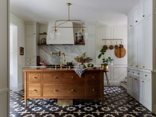 Walnut island in a white kitchen with a patterned tiled floor