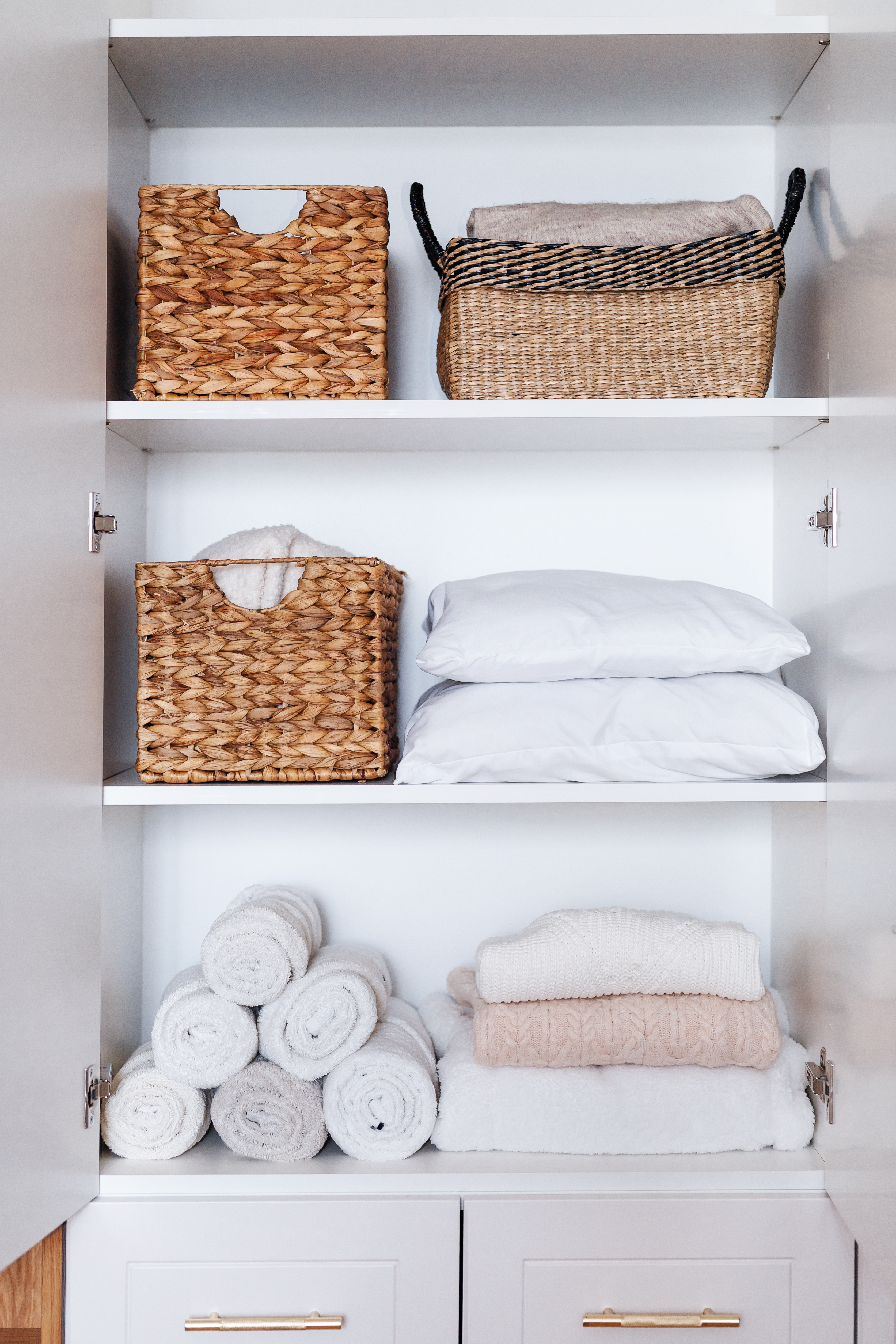 A clean closest with folded towels and bins
