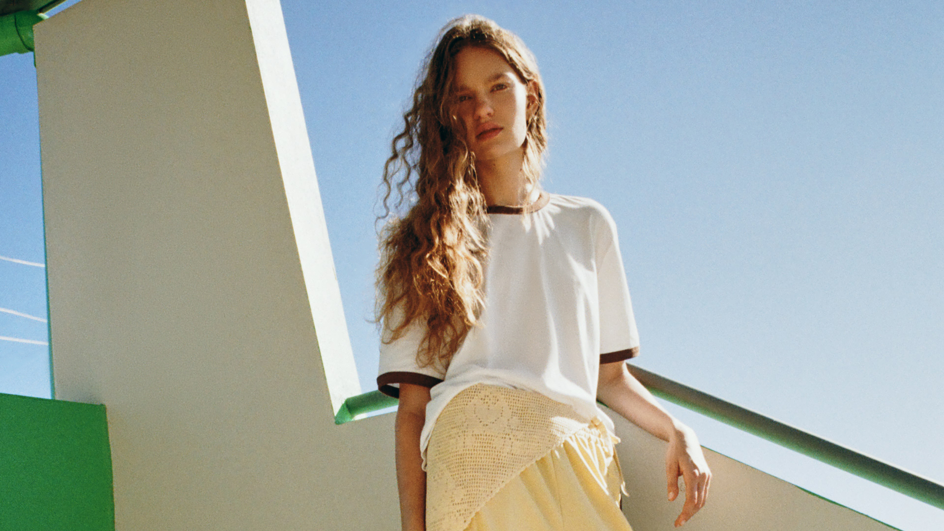A model wearing a white baseball T-shirt with brown trim and yellow shorts from Loeffler Randall's Long Weekend Collection.
