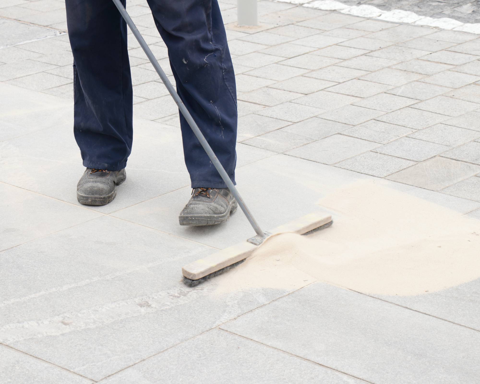 Man applying polymeric sand to pavers
