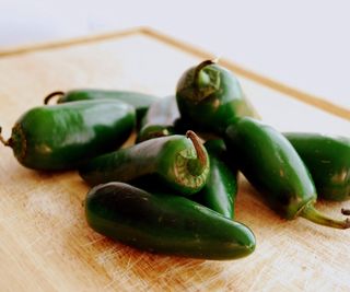 Ripe green jalapeno peppers on a wooden board