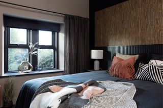 Guest bedroom with black extended panelled headboard and brown feather-effect wallpaper