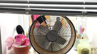 Fan on windowsill with blinds drawn