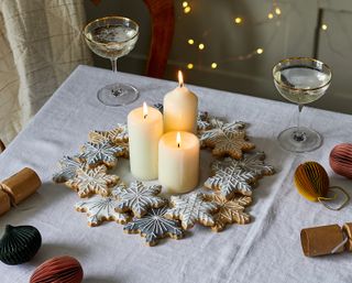 a dining table wreath made out of snowflake biscuits with three candles in the centre
