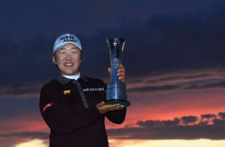 Jiyai Shin holds up the 2012 Women's Open trophy with a sunset background after her win