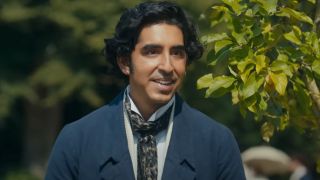 Dev Patel stands smiling in the sunshine dressed in period wardrobe in The Personal History of David Copperfield.