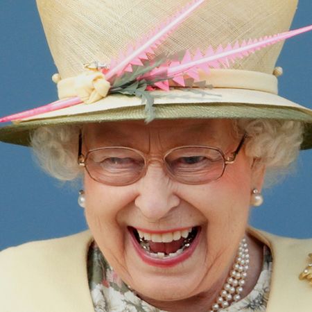 Queen Elizabeth wearing a yellow hat and coat laughing
