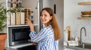 Woman smiling and organizing a tidy kitchen