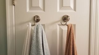 towels hanging on the back of a bathroom door