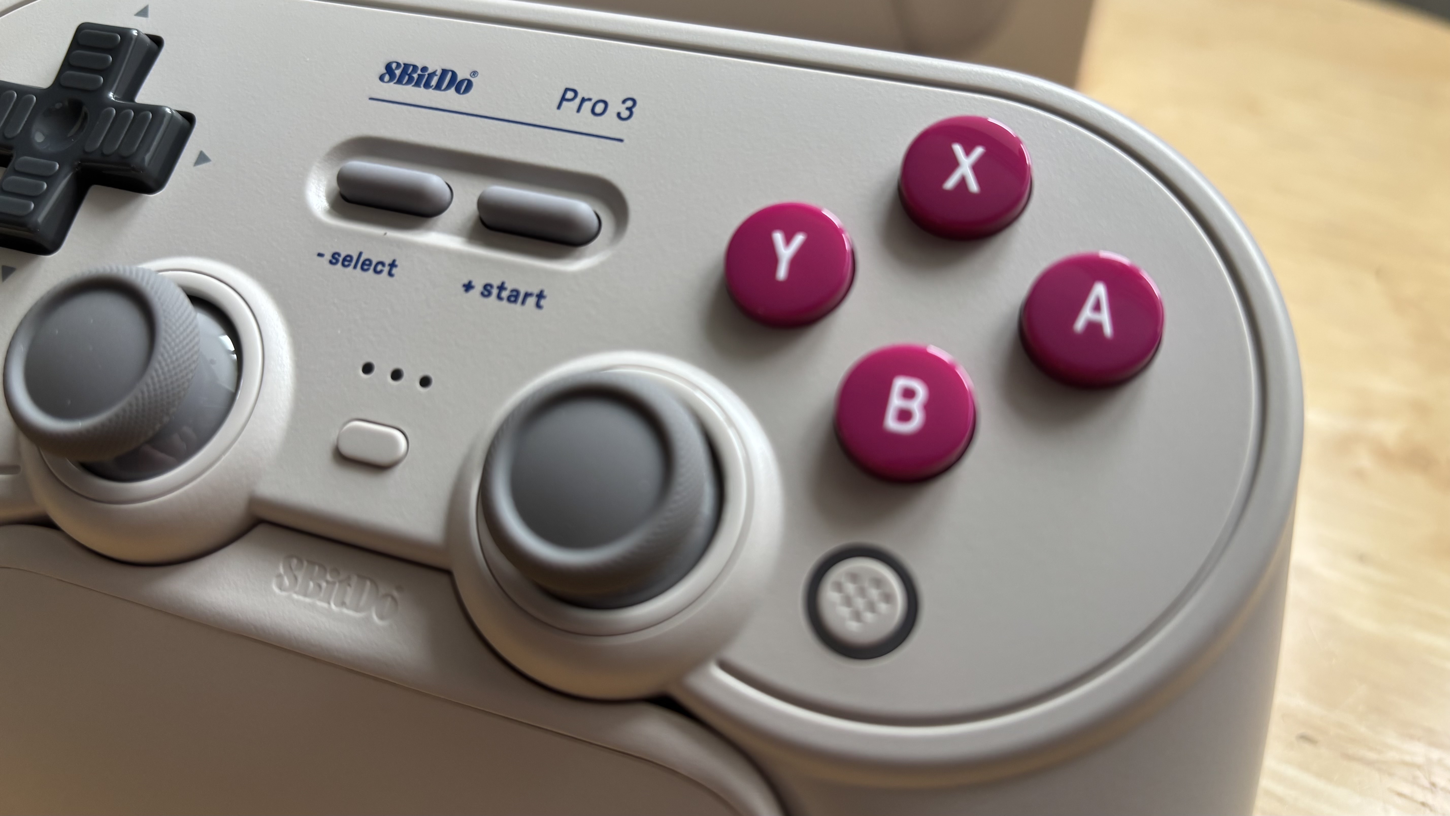 The 8BitDo Pro 3 controller photographed on a wooden table.
