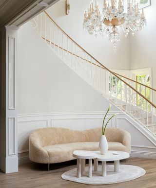 grand curved staircase with chandelier white walls and ivory curved sofa