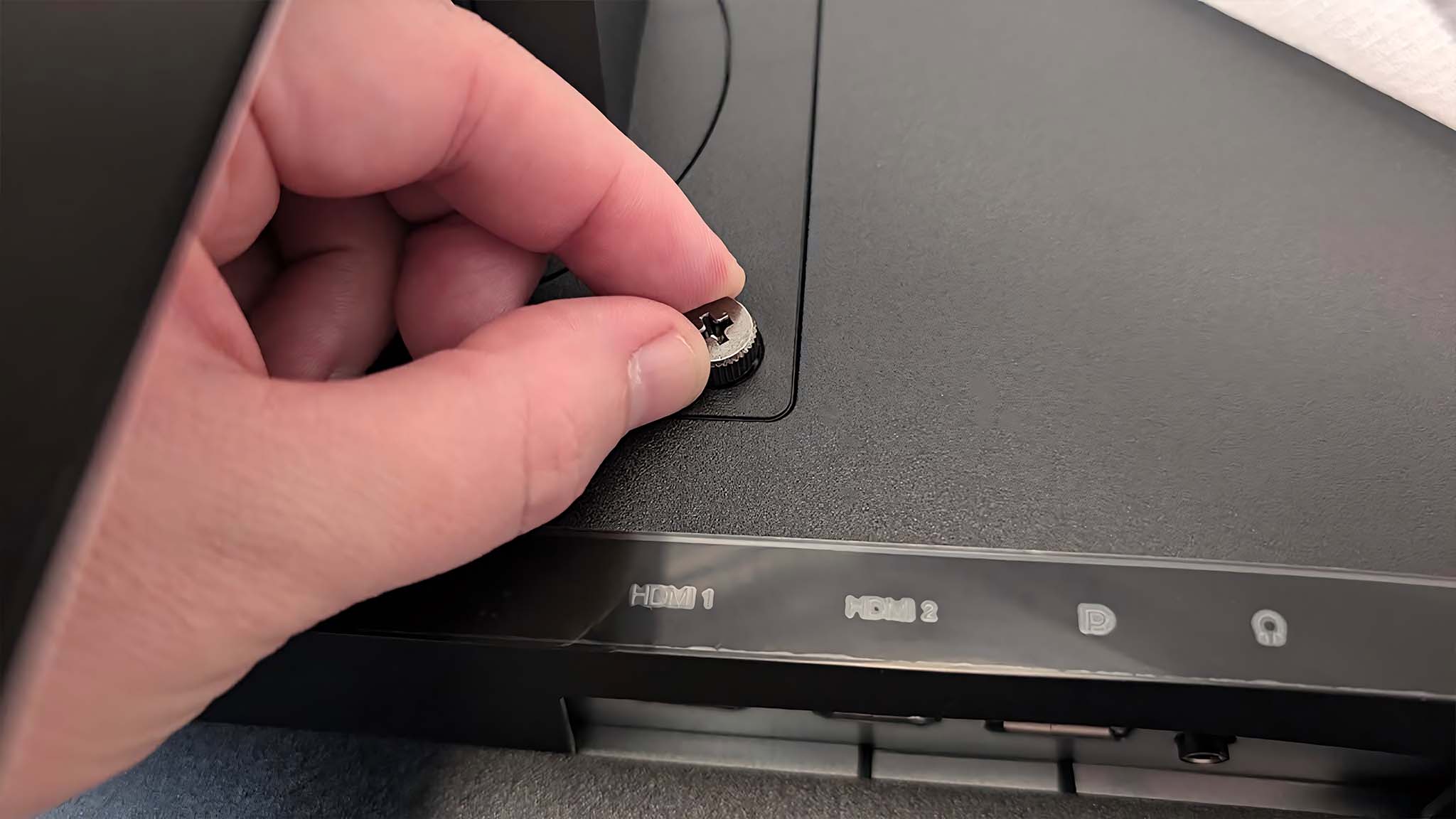 Image showing a hand tightening a screw on the back of the Lenovo Legion R27fc-30.