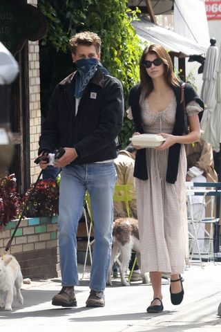 Kaia Gerber walking with Austin Butler while wearing a Dôen dress and mary jane flats